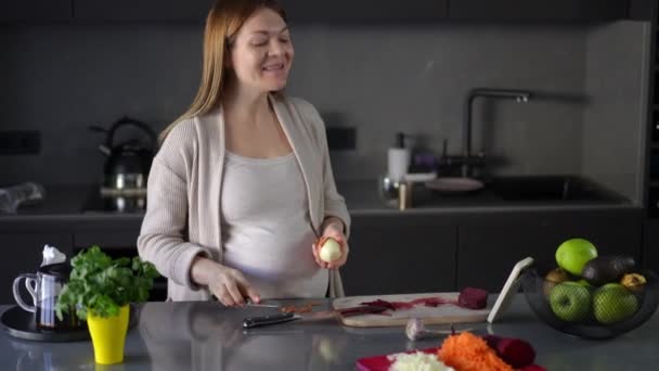 Egy Boldog Terhes Meghámozza Hagymát Egy Konyhakéssel Videón Keresztül Kommunikál — Stock videók