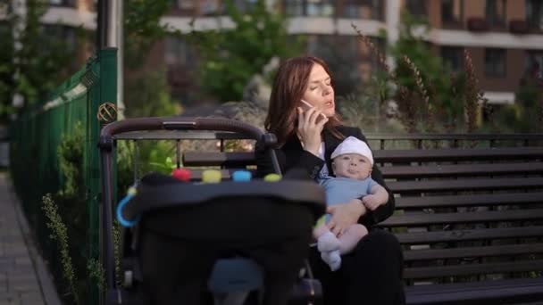 Uma Mulher Negócios Senta Banco Com Bebê Nos Braços Livre — Vídeo de Stock