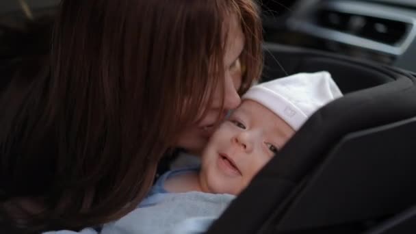 クローズアップ 女性が車の座席に横たわる赤ん坊にキスし 赤ん坊に対する愛とケアを表現しています — ストック動画