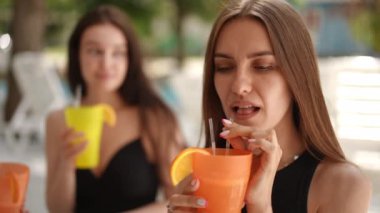 Ağır çekim. Yakın plan. Uzun saçlı tatlı bir kız kokteylden zevk alır, kokteyl pipetinden içer, açık havada bir yaz günü barın tezgahında oturur. Kız çok bitkin görünüyor.
