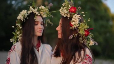 Portrait of two women on the eve of the celebration of Ivan Kupala on a summer evening. Ukrainian women standing in an embrace on the sandy shore in a traditional Ukrainian embroidered shirt and a