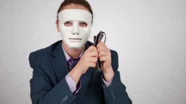 Ağır çekim. Mavi takım elbiseli ve yüzünde beyaz bir maske olan tanınmayan bir kadın kameraya elinde tuttuğu boş ve delikli bir cüzdanı gösteriyor. Bir kadın başını sallıyor ve kameraya bakıyor.