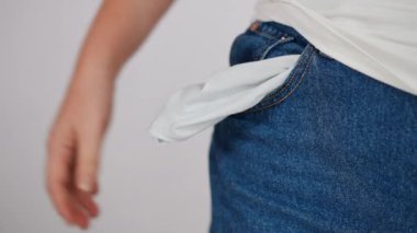 Yakın plan. Bir kadın cebi açık kot pantolon giyiyordu. Kadın elini cebine koyar, astarını düzeltir.