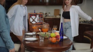 Dört arkadaş modern bir mutfağın sehpasında oturmuş kendi aralarında konuşuyorlar. Bir kız mutfak bıçağını alır ve pizza kesmeye başlar.