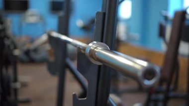 Yakın plan. Spor salonundaki spor egzersiz makinesinin üzerinde metal bir krom halter var.