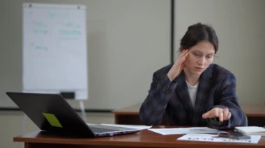 Spor ceketli genç bir kadının ofisinde masasında otururken cep telefonu ekranına dik dik bakan kötü bir baş ağrısı var. Kadın uzanıp rahatlamaya çalışırken sandalyesine yaslanıyor.