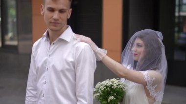 Yüzü peçeli gelinlik giymiş bir gelin nişanlısına arkadan yaklaşır ve elini omzuna koyar. Damat geline döner, duvağı kaldırır ve sevgiyle yüzüne bakar.