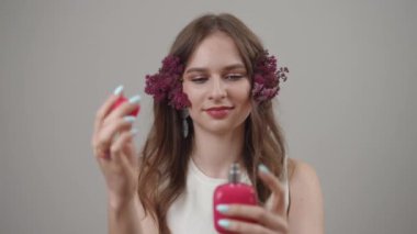 Zarif bir model, saçlarındaki hoş çiçek aksanıyla tamamlanmış canlı bir kozmetik ürünü sergiliyor.