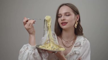 Çekici bir manken, lezzetli bir spagetti tabağının keyfini çıkarıyor, ve kesinlikle nefis bir yemek anını sergiliyor.