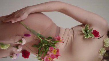 Canlı çiçeklerle süslenmiş, doğal güzelliğin özünü kutlayan çıplak bir figürün güzel bir tasviri.