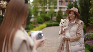 Zarif bir kadın, sevimli ve hoş bir açık hava fotoğraf çekimi sırasında küçük köpeğiyle zarif poz verir.