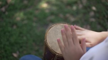 Yeşillik yeşil doğal ortamlarla dolu bir ortamda ellerin ritmik bir şekilde davul çalmasını yakından izlemek.