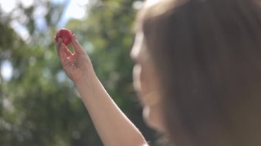 Bir insan küçük kırmızı bir nesneyi havaya kaldırırken doğal bir doğa ortamında doğanın tadını çıkarıyor.