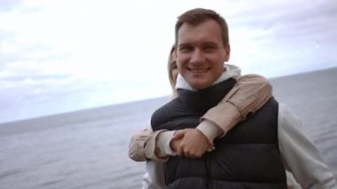 Ağır çekim. Sahilde kucaklaşan neşeli bir çift neşe ve derin bağlarla dolu güzel bir anın tadını çıkarıyor.