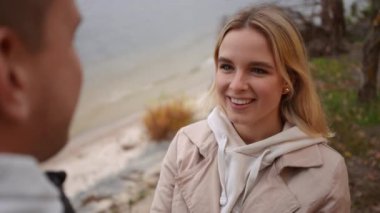 İki mutlu arkadaş, derin bağlantılarını gösteren samimi bir anı yakalayan dingin bir göl kenarında ışıl ışıl gülümserler.