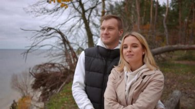 Bir çift birlikte dururlar sakin bir göl kenarında, sonbaharın cazibesini ve özel bağlantılarını güzel bir şekilde somutlaştırırlar.