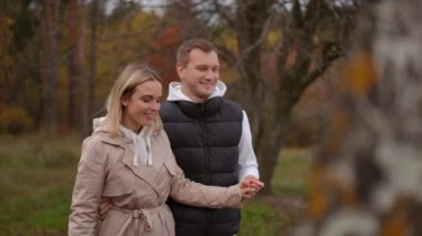 Ağır çekim. Bir çift, sonbahar boyunca doğada manzarayı aydınlatan renkli ağaçlarla çevrili neşeli bir anın tadını çıkarıyor.
