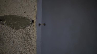 Dokulu beton bir duvara çivi çakılmış. Çevredeki ayrıntıları vurguluyor.