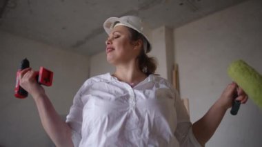 Bir kadın, işlek bir inşaat sahasında, güçlendirmeyi ve aktif yenilemeyi sembolize eden aletleri güvenle sergiliyor