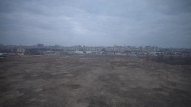 Uzak bir şehir silueti olan ıssız bir arazi, doğa ve şehirleşme arasındaki zıtlığı vurguluyor..