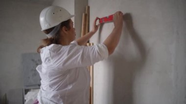 Sert şapkalı kendine güvenen bir kadın, ticaret sektöründe güç gösterisi yapan bir inşaat alanını teftiş ediyor.