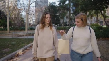 Kara Cuma indirimi. İki yakın arkadaş güzel parkta keyifli bir yürüyüş yapar, sohbet eder ve alışveriş çantalarını taşırlar.