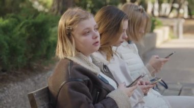 Sakin bir açık hava ortamında akıllı telefonları kullanarak sohbet eden arkadaşlarımızın sıradan bir araya gelmesi.