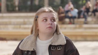 Düşünceli ve düşünceli genç bir kız canlı bir şehir atmosferinde yukarı bakar, derin duyguları yakalar.