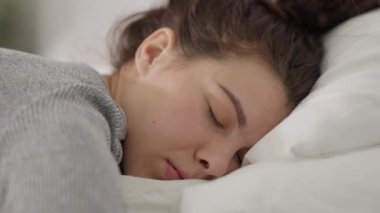 Huzurlu ve huzurlu bir an. Yumuşak ve rahat bir yastıkta huzur içinde uyuyan bir kadın.