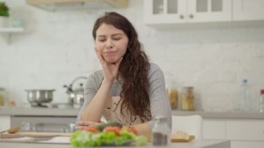 Düşünceli bir kadın sıcak mutfağında durup besleyici bir yemek için titizlikle taze sebzeleri hazırlıyor.