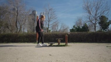 Açık mavi gökyüzü ve yemyeşil ağaçları olan sakin ve huzurlu bir park. Aktif dinlenme ve açık hava egzersizleri için ideal. Güzel bir kız koşu bandında yürüyor.