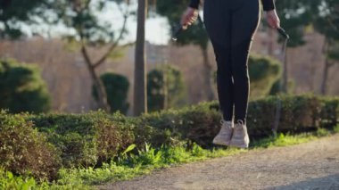 Bir kadın tamamen meşgul ve sakin ve sakin bir açık havada ip atlama egzersizinden zevk alıyor.