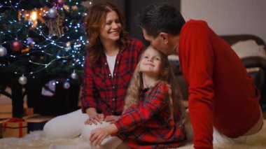 Neşeli bir aile, Noel boyunca neşeli dekorasyonlarla çevrili, iç açıcı bir anı paylaşır..