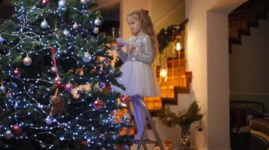 Ağır çekim. Sevimli beyaz çocuk Noel ağacına Noel Baba 'ya mektup bırakıyor, Noel ruhuna, bayrama ve kutlama konseptine hazırlanıyor.