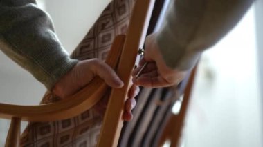 Mükemmel işçilik ve detayların altını çizerek, iyi hazırlanmış ahşap bir sandalye çerçevesini kavrayan ellerin yakınlığı