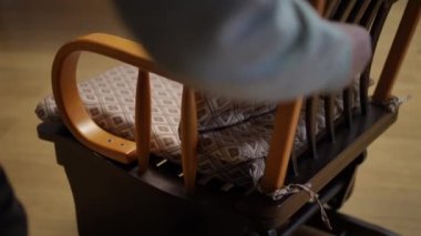 Çok güzel hazırlanmış sallanan bir sandalyeye yakın plan, canlı bir yastıkla, huzur ve sükuneti çağrıştıran