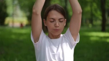 Genç bir kadın dingin bir parkta yoğun yoga hareketleri sergiliyor. Elleri sıkıca bağlı ve gözleri kapalı, derin bir şekilde nefesine ve hareketlerine odaklanıyor, güç yayıyor ve...