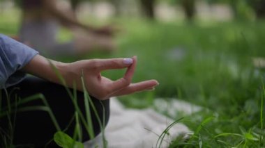 Hafif lavanta ojeli bir kadının yakın çekimi meditasyon jestinde, yoga sırasında huzur parkında dizinde dinleniyor. Zarif manikür biraz incelik katıyor.