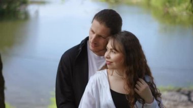 Bir çift, doğal güzellikler ve büyüleyici manzaralarla çevrili sakin bir göl kenarında sevgi dolu bir anı paylaşıyor.