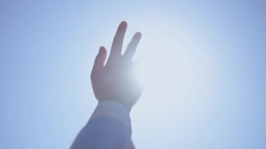 Bir el yukarı uzanıyor parlak ve açık mavi gökyüzüne, umudu, hayalleri ve hayattaki tutkuları simgeliyor.