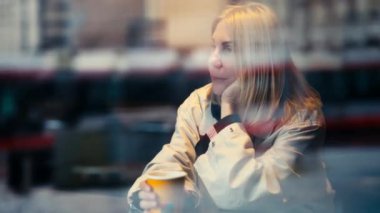 Bir kadın Madrid 'de bir kafede oturmuş, akıllı telefonu ve bilgisayarı olmadan huzurlu bir anı kucaklıyor. Pencereden, kentsel sokak yansımaları onun dingin varlığıyla harmanlanmış, özgürlüğü simgeliyor.