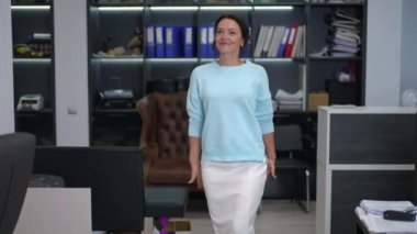 Profesyonel bir kadın şık ve modern bir ofis ortamında zarafet ve soğukkanlılıkla yürüyor.