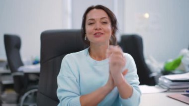 Kendine güveni tam bir kadın şık masasında oturuyor, parlak, modern ofis alanındaki profesyonelliği açıkça gösteriyor.