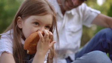 Bir kız, yemyeşil bir parkta keyifli bir atıştırmalığın tadını çıkarıyor. Sevdiği biriyle keyifli bir anı paylaşıyor.