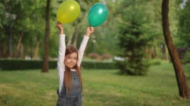 Yeşil bir parkta renkli balonlar tutan mutlu bir çocuk saf neşeyi ve oyunculuğun özünü simgeliyor.