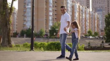 Bir baba ve kızı şehirde güneşli bir yürüyüş yaparak aile sevgisi ve bağının özünü yakalıyor..