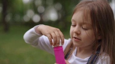 Neşeli bir çocuk neşeyle parlak ve parlak bir solüsyonla güneşli mavi gökyüzünün altında renkli baloncuklar yaratıyor.