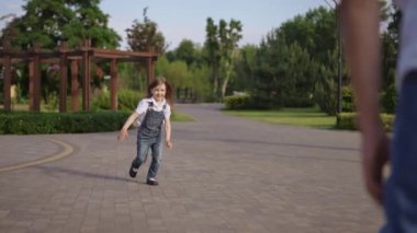 Geniş bir parkta tek başına duran küçük bir çocuk yetişkin bir şahsiyet onlara yaklaşıp onlara doğru yürüyor.