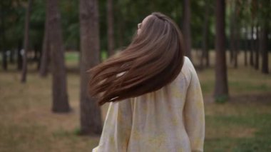 : Bir kadın zarif bir şekilde uzun, parlak, keratin zengini saçlarını savurarak pürüzsüz dokusunu ve canlı sağlığını sergiliyor. Sakin bir ormana kurulmuş, akan iplikleri, su kaybının faydalarını yansıtıyor.