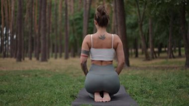 Huzurlu bir kadın gür bir ormanda yoga yapıyor, dengesini ve doğayla derin bağını gösteriyor.